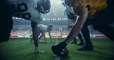 Two Diverse American Football Teams Play a Dynamic Match in Soaking Wet Weather in Front of a Stadium Filled with Spectators. Players Making a Stand-Off Before Quarterback Passes the Ball