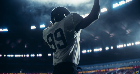 Black Football Player Celebrating Victory in Stadium, Wearing a White Jersey with Number 99....