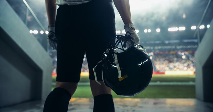 Dramatic Football Walkout: Successful Player Entering a Massive American Football Stadium to the Noise and Cheering of the Anticipating Fans. Epic Close-Up Back View of an Anonymous Athlete
