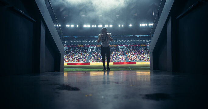 Portrait of a Professional Footballer in White Uniform Walking Away From a Stadium in a Tunnel. Best Player is Celebrated by a Full Arena of Sports Fans in a Big Outdoors Stadium
