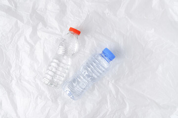 Empty small mineral water bottles laid on crumpled and wrinkled plastic sheets. Concept for zero waste and micro plastic pollution.