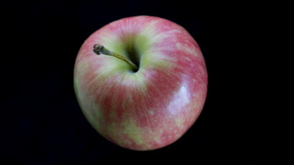 A Fresh Red Apple contrasts beautifully with a Black Background, showcasing its appeal