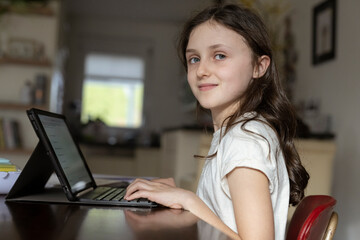 Mädchen, 10 Jahre, sitzt mit Tablet am Tisch und lernt