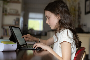 Mädchen, 10 Jahre, sitzt mit Tablet am Tisch und lernt
