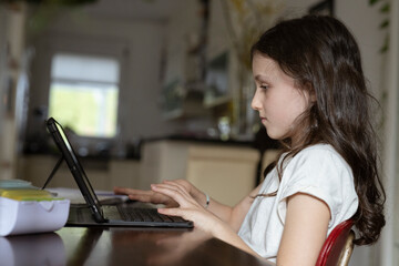 Mädchen, 10 Jahre, sitzt mit Tablet am Tisch und lernt