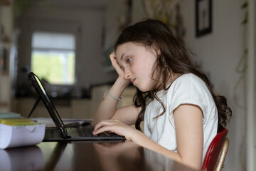 Mädchen, 10 Jahre, sitzt mit Tablet am Tisch und lernt