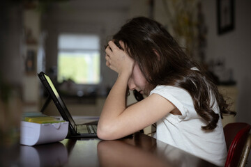 Mädchen, 10 Jahre, sitzt mit Tablet am Tisch und lernt