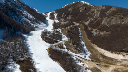 Aerial view of a ski slope. It is a sunny autumn morning and there is  snow on the mountain. 