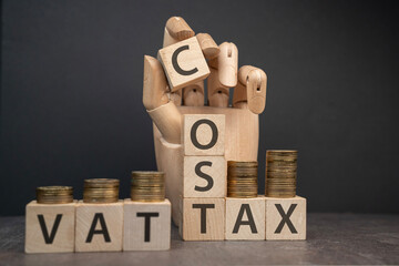 sztuczna dłoń układająca napisy dotyczące finansów: VAT, COST, TAX
