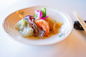 Japanese seafood appetizer featuring fresh shrimp, mollusks, and fermented vegetables, served in a traditional ceramic dish with wasabi garnish and pickled toppings