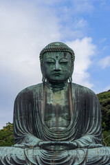 Historic bronze Buddha statue at Kotoku-in temple in Kamakura Japan sitting in a meditation posture with intricate details and a weathered surface