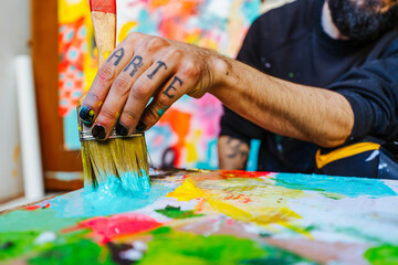 Artist’s Hand Mixing Paint with a Brush on a Palette. Close-up of an Argentine artist’s hand...