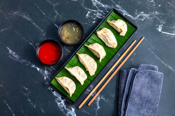 Momo are steamed or fried dumplings filled with meat or vegetables, popular in Nepal, Tibet, and Bhutan, served with spicy chutney.