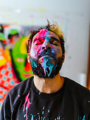Artist Immersed in Colors with Paint-Splattered Face. A creative artist with eyes closed, his face...