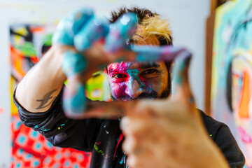 Creative Artist Framing His Vision with Painted Hands. A passionate artist with paint-covered hands...