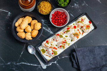 Dahi Bhalla is a popular Indian snack made of deep-fried lentil dumplings soaked in creamy yogurt, topped with tangy chutneys, spices, and pomegranate.