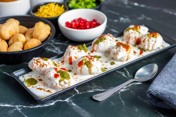 Dahi Bhalla is a popular Indian snack made of deep-fried lentil dumplings soaked in creamy yogurt, topped with tangy chutneys, spices, and pomegranate.