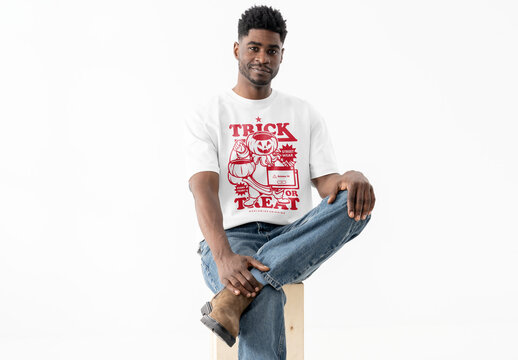Mockup Of Man Wearing Customizable T-Shirt In Studio, Leg Crossed