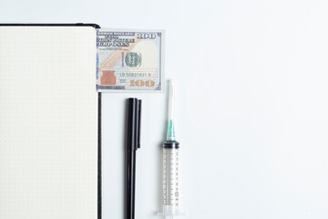 Creative flatlay of doctor medical equipment, white table with books, dollar bills, syringe and black pen. Health care cost concept, Top view with copy space, Isolated on white.