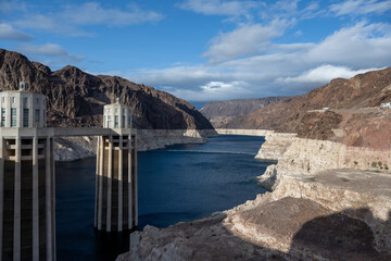 Das Bild zeigt eine ruhige Szene an einem Staudamm in einer w&uuml;sten&auml;hnlichen Umgebung mit zwei T&uuml;rmen auf beiden Seiten eines Flusses 