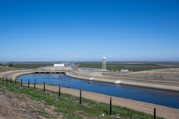 Das Bild zeigt die ruhige Szene eines landwirtschaftlichen Gebiets unter strahlend blauem Himmel. 