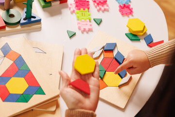 Child and parent playing with a colorful wooden educational toy, improving motor skills and...