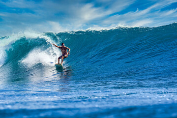 Male surfer on a blue wave at sunny day