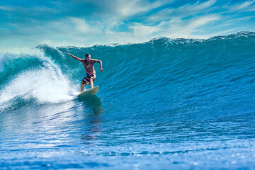 Male surfer on a blue wave at sunny day