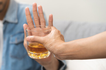 Alcoholism, depressed asian young man refuse, push out alcoholic beverage glass, drink whiskey, sitting alone at night. Treatment of alcohol addiction, having suffer abuse problem alcoholism concept.
