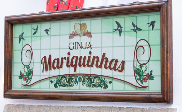 Obidos, Portugal - 17 August 2021: Ginja Mariquinhas brand displayed on a colorful board with traditional portuguese tiles. Ginja or Ginjinha is a typical portuguese liquor