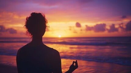 Silhouette of woman practicing yoga on beach at sunset