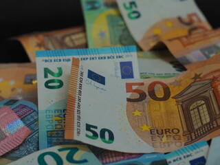 Разбросанные евро-купюры разного номинала на черном фоне. Фокус на деталях дизайна