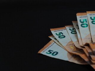 50 Euro bills are arranged in a fan on a black background. Design elements, denominations and security features are clearly visible.