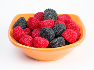 group of assorted red and black gummy candies are contained in an orange bowl