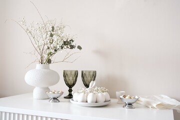 A stylish table with white eggs, colorful flowers in elegant vase, and elegant glassware ideal for spring gatherings. Easter consept.