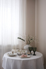 A beautifully arranged table with delicate flowers, desserts, and vintage glassware, creating a serene easter atmosphere.