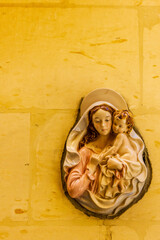 Virgin Mary and Child Bas-Relief on Wall with Warm Yellow Background