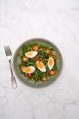 A vibrant and colorful salad featuring fresh greens arugula, diced tomatoes, sweet peas, and softboiled eggs cooked perfectly.