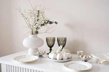 A stylish table with white eggs, colorful flowers in elegant vase, and elegant glassware ideal for spring gatherings. Easter consept.