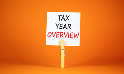 Tax year overview symbol. Concept words Tax year overview on beautiful white paper on clothespin. Beautiful orange background. Business tax year overview concept. Copy space.