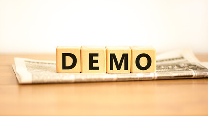 Demo symbol. Concept word Demo on beautiful wooden blocks on newspaper. Beautiful wooden table...