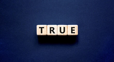 True symbol. Concept word True on beautiful wooden blocks. Beautiful black table black background....