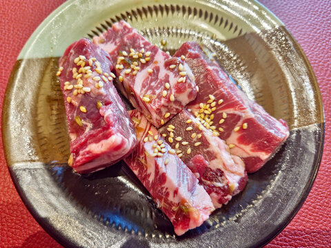 Raw outside skirt beef (Gyu Harami) elegantly presented on a plate and garnished with sesame seeds. Perfect for Japanese barbecue (Yakiniku).