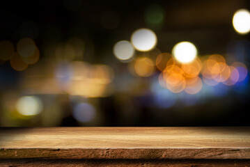 empty wooden table top on blur light golden bokeh of cafe restaurant, bar in a dark background, for your photo montage or product display, Space for placing items on the table.
