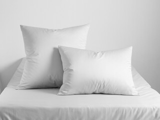 Two white pillows on the bed, covered with a white sheet, there are two white pillows with pillowcases. Front view photo. Suitable for mockup