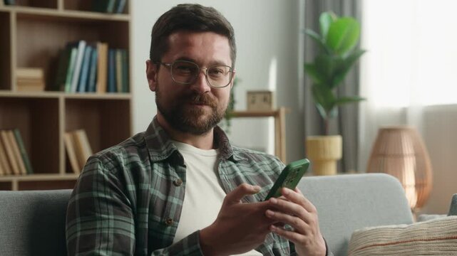 Caucasian man male guy smiling showing green screen smartphone display app at home demonstrate thumb up recommend like good online shopping website chroma key mobile phone bet gambling sport casino