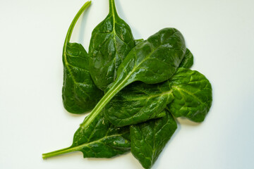 Fresh spinach leaves on a white background. The minimalist style highlights the natural quality and health benefits of greens, symbolizing a healthy diet and spring freshness.