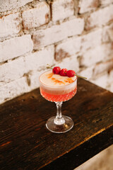 Delicious raspberry cocktail served in a crystal glass on a rustic wooden table