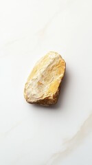 An isolated rock rests on a white marble patterned surface