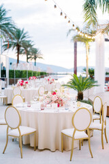 White chairs stand around a round festive table with a bouquet of flowers